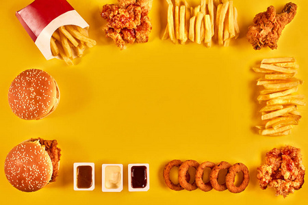 顶视图汉堡包 炸薯条和炸鸡在黄色背景上。复制空间为您的文字
