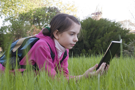少女在草地上读电子图书