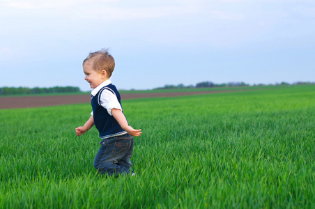 一个美丽的小男孩在草地上奔跑