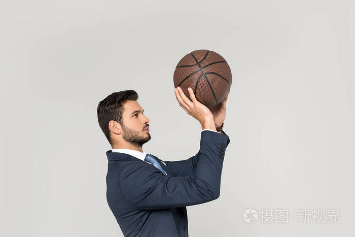 青年商人投掷篮球的侧面看灰色孤立球