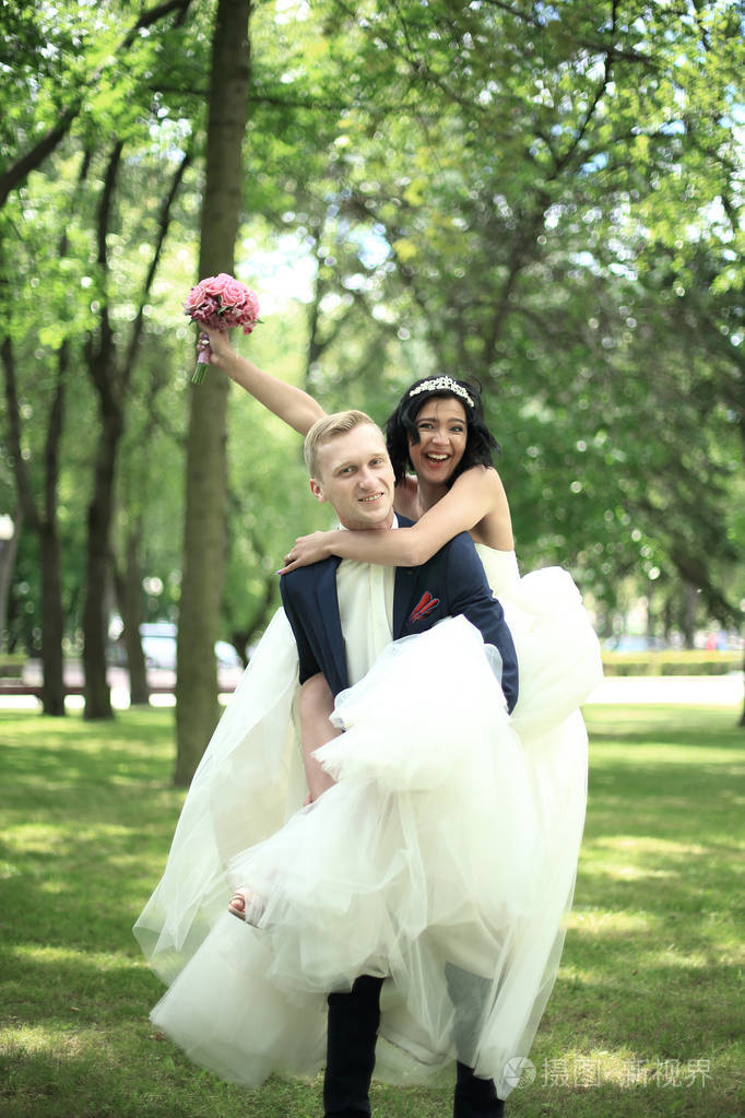 幸福的新郎抱在怀里的他的新娘