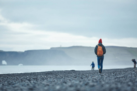 走在 Reynisfjara 黑沙海滩，冰岛南部的女人