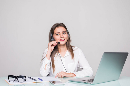 幸福迷人的年轻女人坐和使用笔记本电脑在办公室使用耳机