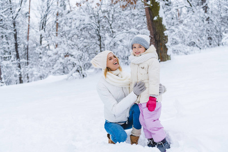愉快的母亲和女儿拥抱在冬天公园