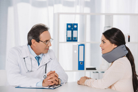 医生坐在和谈话与女性患者在颈支架