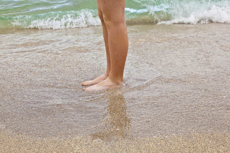 男孩的脚沿着海滩奔跑