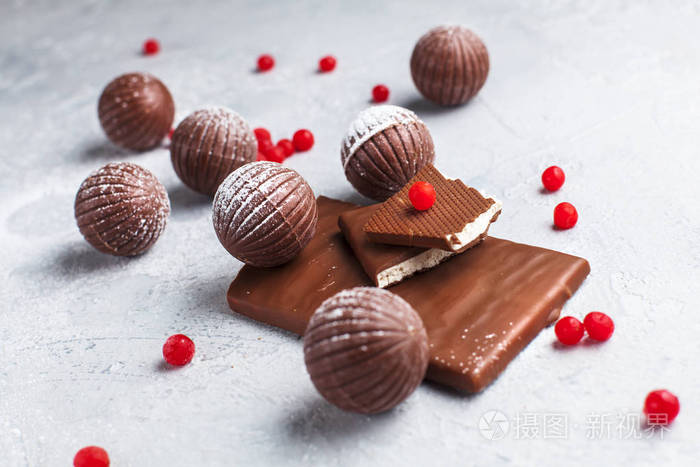 巧克力圆形糖果巧克力棒和红色浆果的灰色背景和糖粉