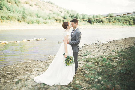 优雅温柔时尚新郎和新娘用石头河附近。婚礼热恋中的情侣