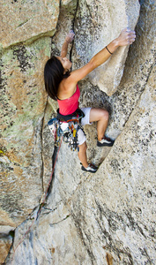 紧紧抓住悬崖的女性登山者。