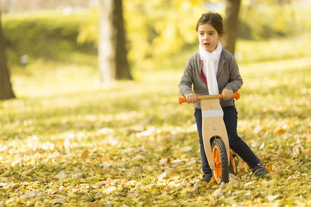 秋天公园的小女孩骑自行车