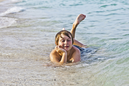 男孩喜欢躺在沙滩上冲浪