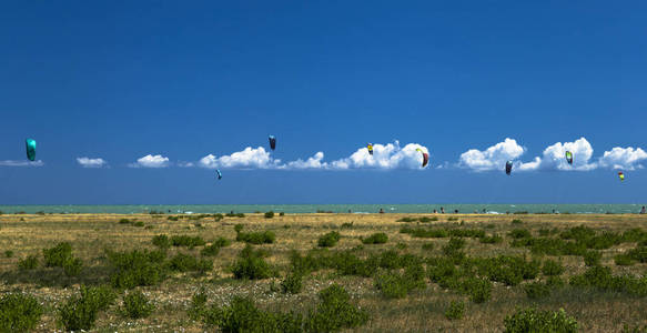 Kitesurfers 在下美丽的云彩海滩航行的全景视图