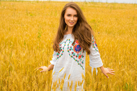 年轻的女子在金黄的麦田背景