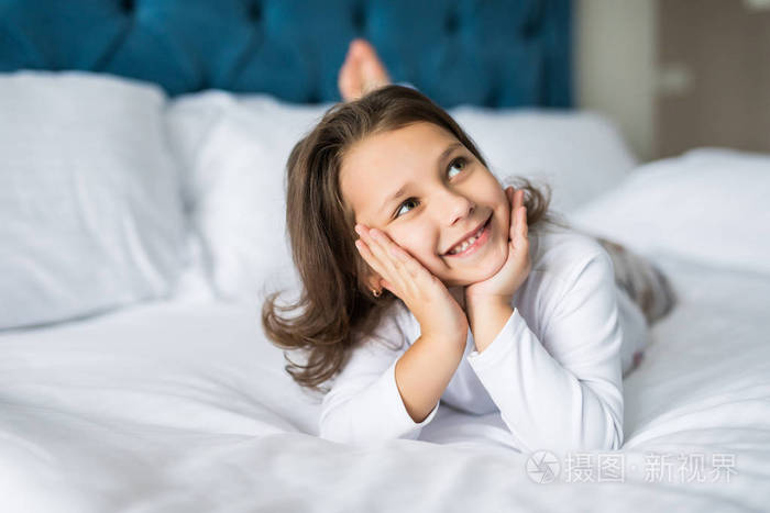 可爱的微笑的小女孩在她的床上醒来