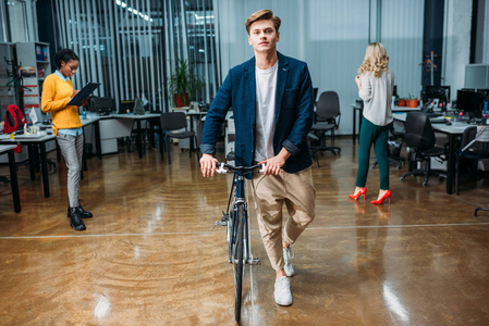 年轻英俊的生意人与自行车步行由现代办公室