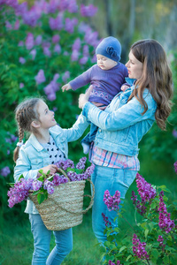 愉快的母亲和女儿与绿色苹果在盛开的紫丁香花园