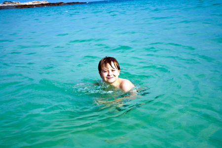 男孩正在美丽的海滩上享受清澈的温水，但