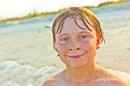 可爱的男孩在暴风雨的海滩上玩得很开心