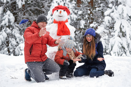 堆雪人的球冬天的乐趣一个女孩, 一个男人和一个男孩堆雪人照片