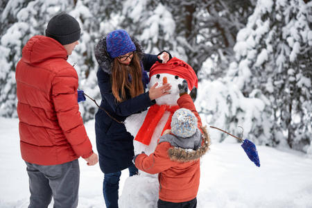 冬天的乐趣一个女孩, 一个男人和一个男孩堆雪人照片