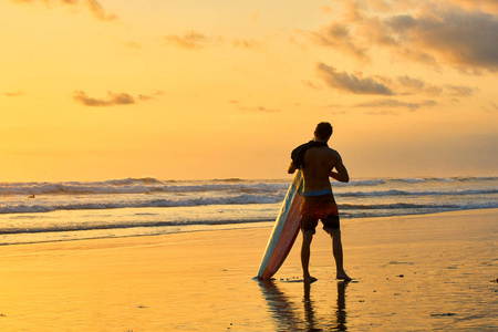 上海洋海滩的日落在印度尼西亚巴厘岛上的冲浪者