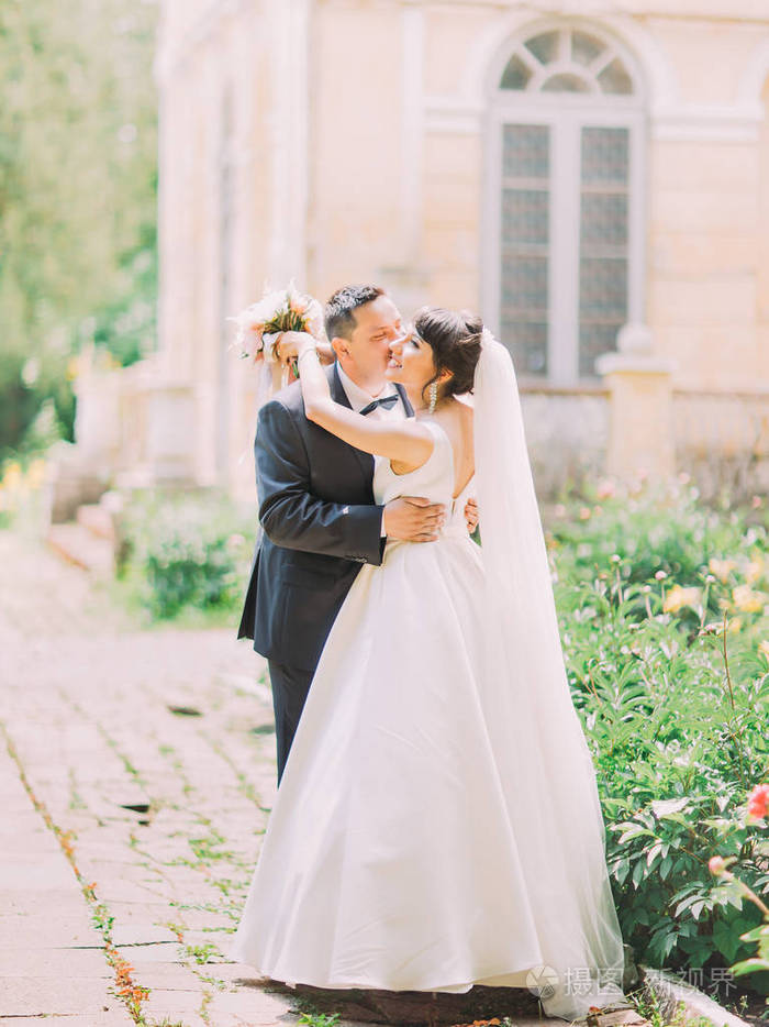 全长的照片的英俊新郎亲吻新娘的脸颊街道位置