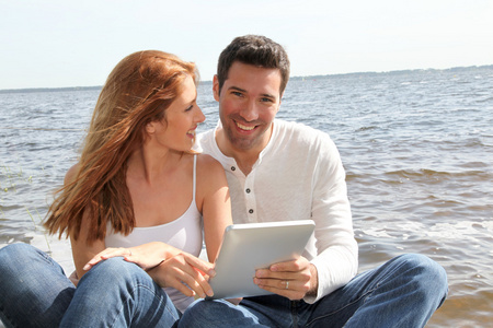 一对夫妇在湖边用电子平板电脑
