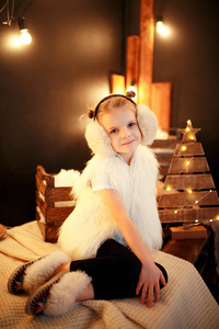 可爱的小女孩在毛皮耳坐在圣诞节树附近