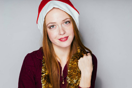 可爱的 redhaired 女孩在一个红色的帽子像圣诞老人庆祝新年, 脖子上的金色金箔