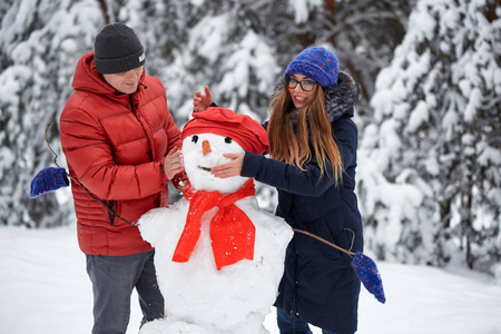 女性制作雪球冬天的乐趣.一个女孩和一个男人在做雪球照片