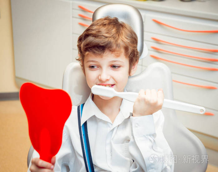 小男孩用大刷子刷牙.在牙科办公室