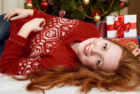 美丽的女孩躺在圣诞装饰。家庭内部, 冷杉树和礼物。新年前夕和寒假概念