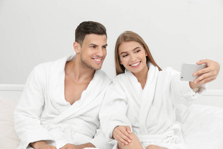 年轻情侣浴袍自拍在酒店床上照片