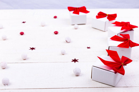 圣诞礼物, 白色的小盒子, 红色的蝴蝶结和糖果在白色的木制背景。圣诞快乐