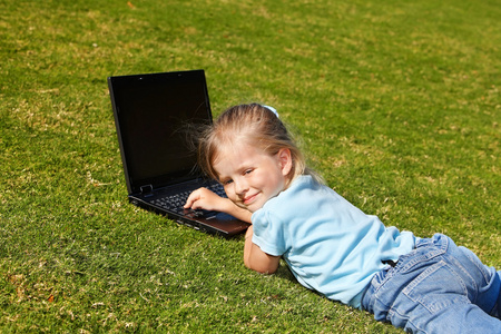 绿色草地上有笔记本电脑的孩子。
