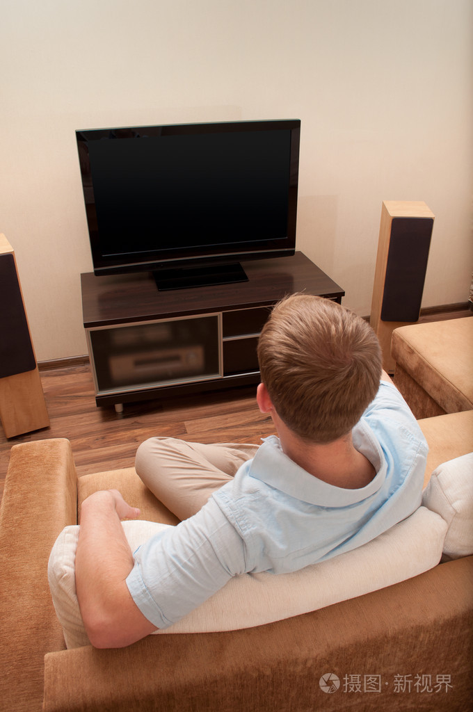 男人躺在沙发上在家看电视