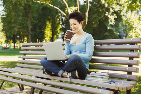 快乐的年轻妇女使用手提电脑在公园