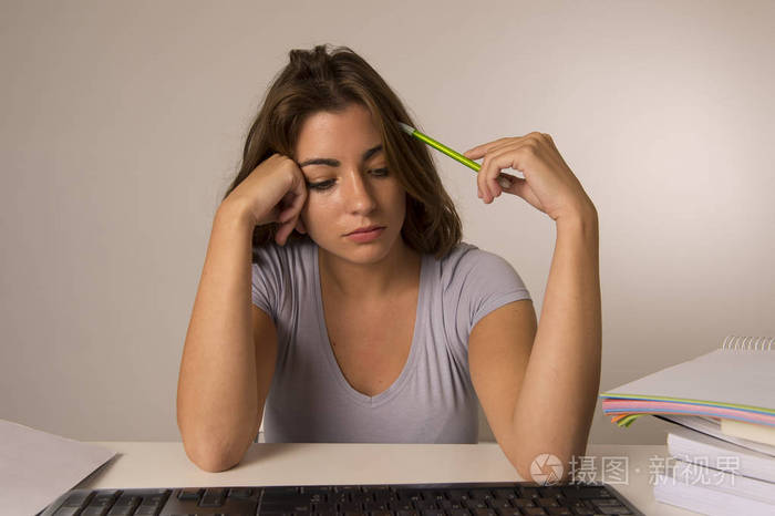 年轻有吸引力的学生女孩或工作的妇女坐在办公桌上的压力看起来疲惫