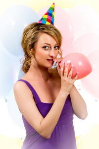 可爱的女孩吹一个粉红色的气球