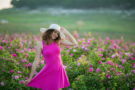 穿着紫色礼服的年轻女子和白色帽子有乐趣摆着花