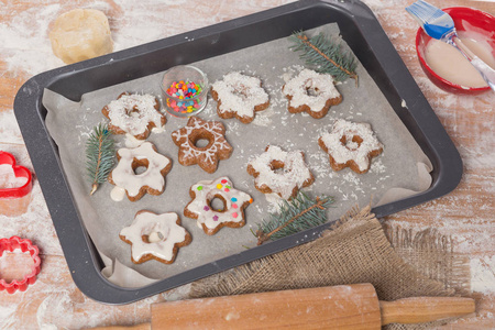 在烘烤板上是完成的圣诞曲奇饼, 饼干形状, 配料, 树枝在桌子上