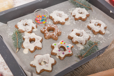 在烘烤板上是完成的圣诞曲奇饼, 饼干形状, 配料, 树枝在桌子上