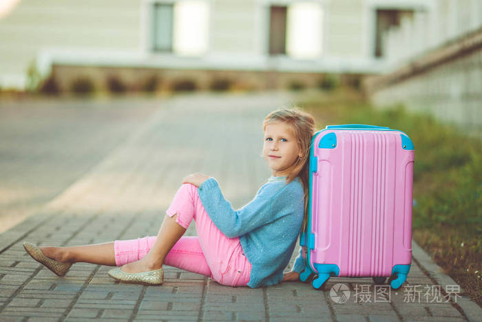 愉快的小女孩与粉红色手提箱准备好旅行