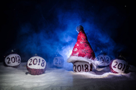 红色圣诞节球与2018数字和圣诞老人条款帽子在自然雪背景。新年快乐2018概念。复制空间。选择性焦点