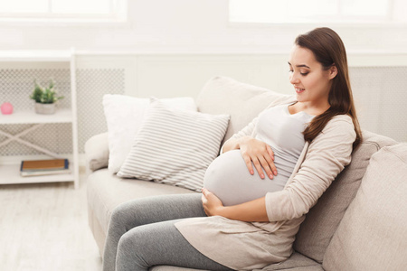 怀孕的妇女在家里爱抚她的肚子
