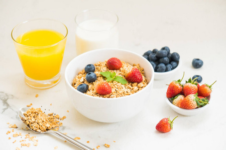健康早餐在白色石桌背景设置燕麦饼与蓝莓和草莓和黑咖啡牛奶和橙汁