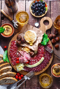 混合不同的小吃和开胃菜 香肠, 面包, 橄榄, 奶酪, 栗子, 豌豆和啤酒的木板。顶部视图