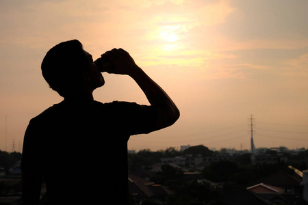 啤酒可以剪影一个男人在夕阳背景下喝着提神啤酒的剪影照片