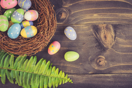 五颜六色的复活节彩蛋在木板木背上的整洁和绿叶