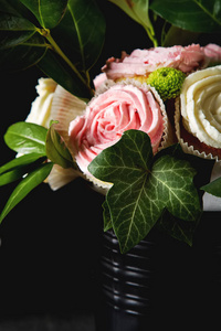 一束蛋糕和绿色的叶子在一个黑色的花盆。暗 b